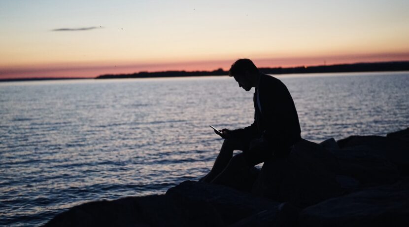 man sitting on rock in front of ocean