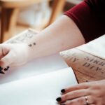 person holding pen above white open notebook page