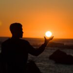 silhouette of man holding sun