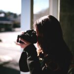 woman holding black DSLR camera