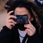 woman in black jacket holding black nikon camera