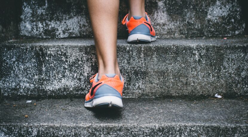 person wearing orange and gray Nike shoes walking on gray concrete stairs