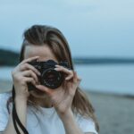 woman in white shirt holding black dslr camera
