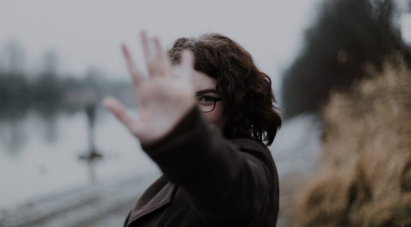 woman in black coat standing near body of water during daytime
