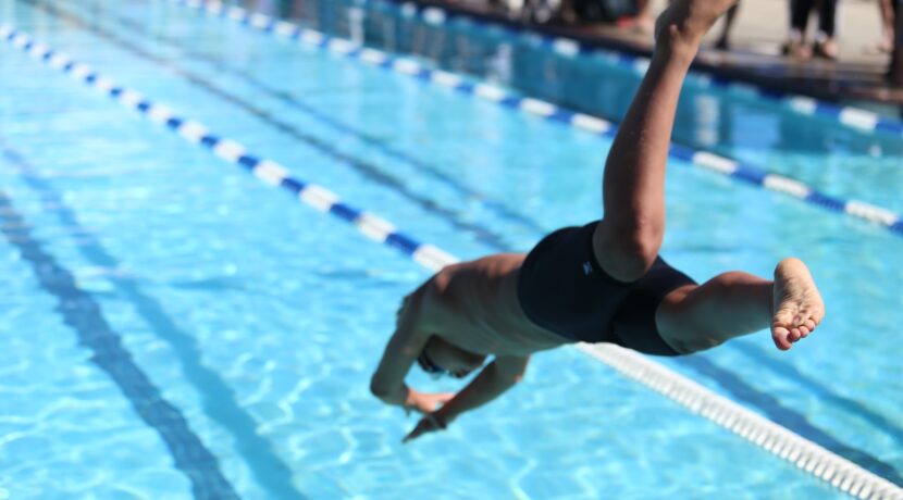 woman in black one piece swimsuit jumping on swimming pool during daytime