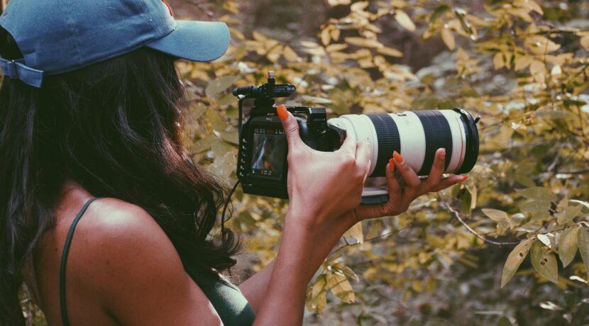 woman in blue cap holding black and white dslr camera