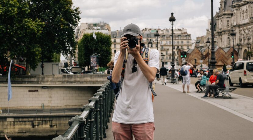 man holding DSLR camera beside bridge