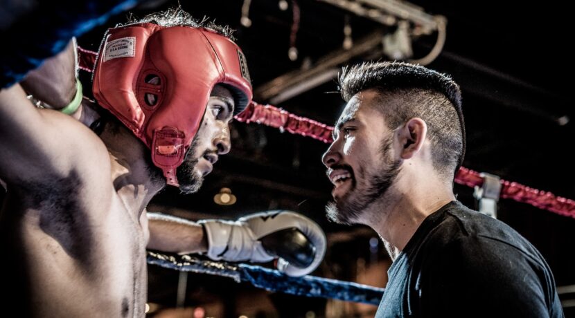 man in black talking to boxer inside ring