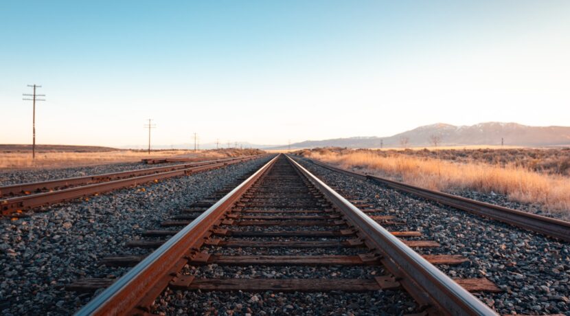 brown train rail under blue sky during daytime