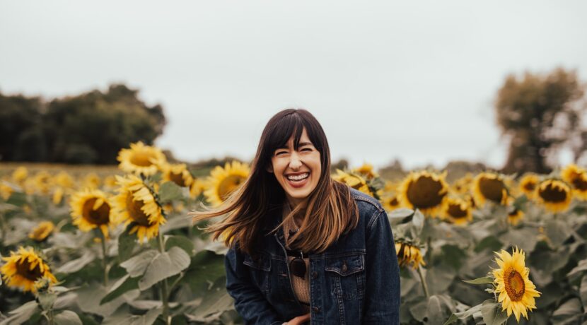 smiling woman standing beside sunflowers