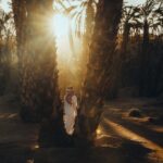 a woman is standing between two palm trees