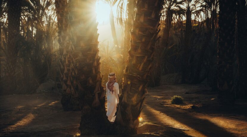 a woman is standing between two palm trees