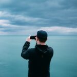 men's black hoodie in front of teal sea