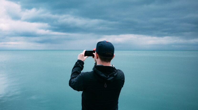 men's black hoodie in front of teal sea