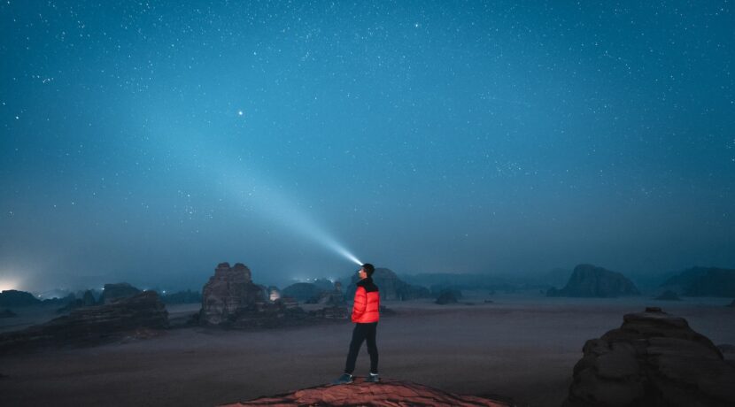 a person standing on top of a rock under a sky filled with stars