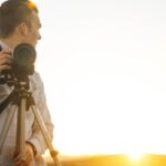 man holding DSLR camera during golden hour