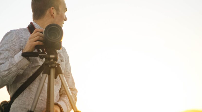 man holding DSLR camera during golden hour