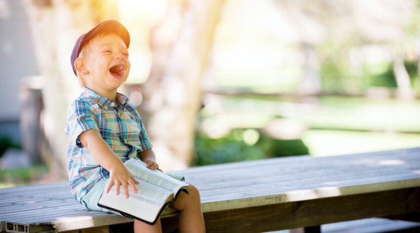 boy sitting on bench while holding a book