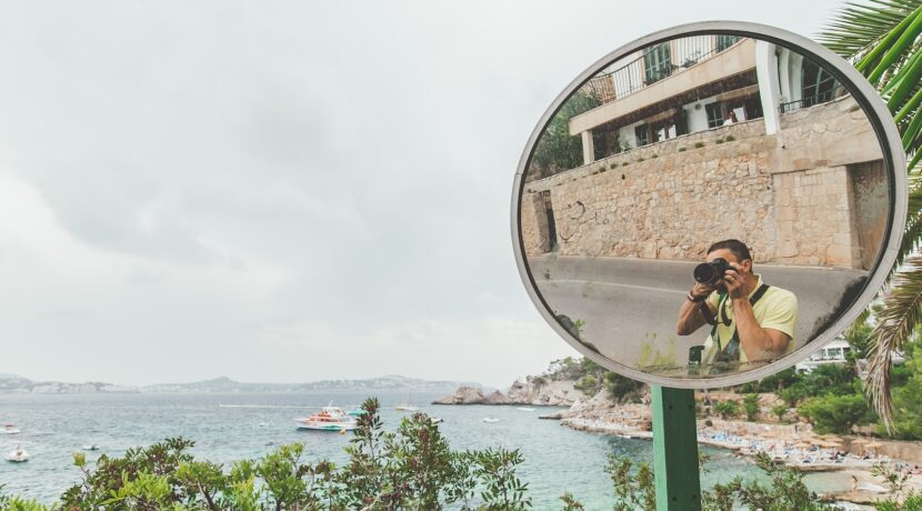 woman in black tank top taking photo of brown concrete building near body of water during