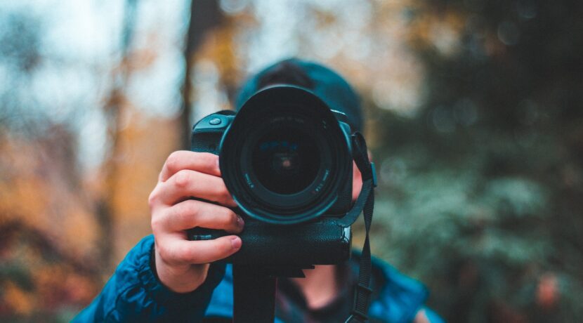 selective focus photography of man holding black DSLR camera