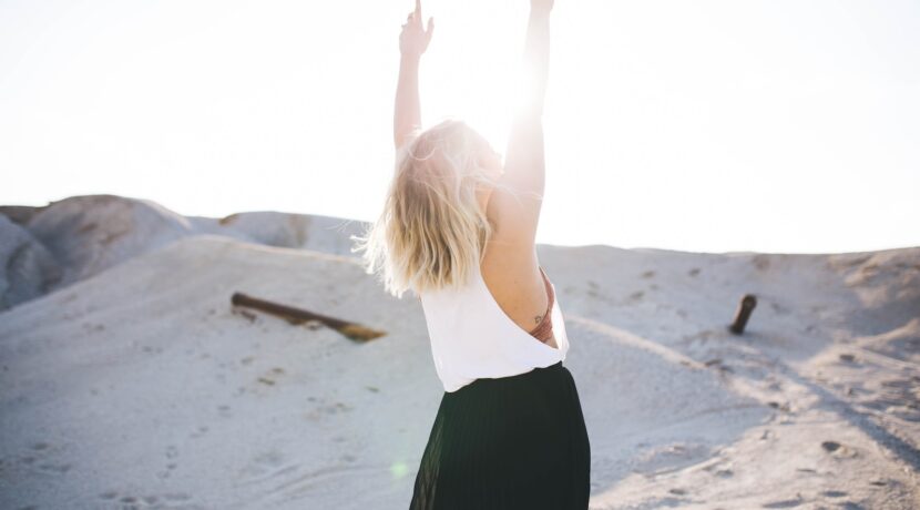 woman standing on the desert while her hands up