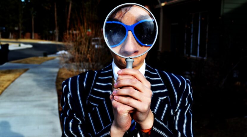 person using magnifying glass enlarging the appearance of his nose and sunglasses