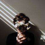 person holding white daisy flowers