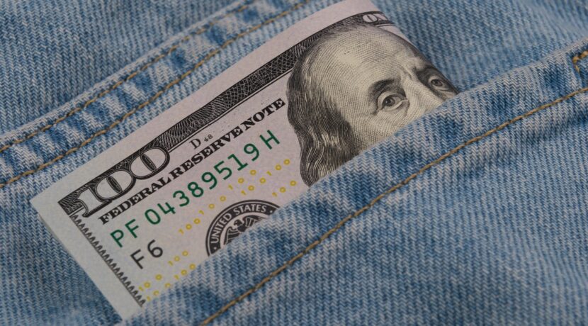 a hundred dollar bill sticking out of the back pocket of a pair of jeans