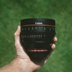 person holding black Canon lens