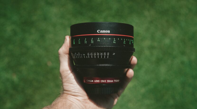 person holding black Canon lens
