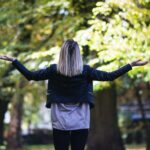 woman in black long-sleeved top in front of green leafed tree