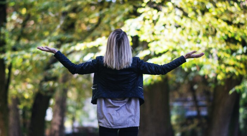 woman in black long-sleeved top in front of green leafed tree