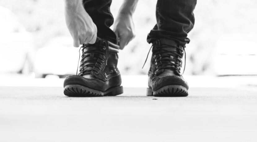 person wearing black leather lace-up boots