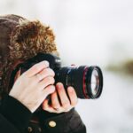 person wearing bomber hat and using black camera