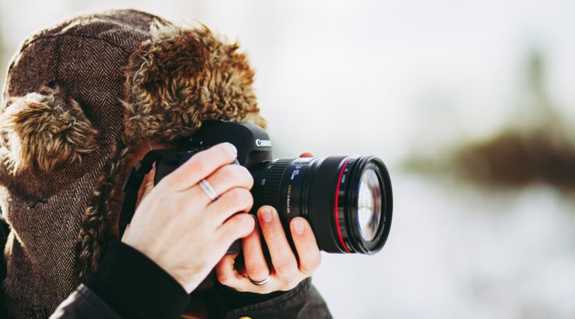 person wearing bomber hat and using black camera