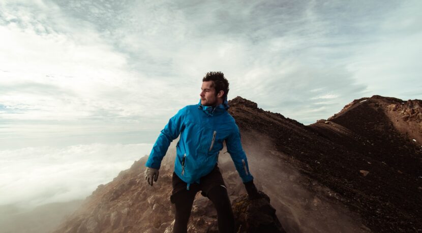 man in blue jacket standing on cliff