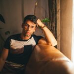 man in black and white crew neck t-shirt sitting on brown sofa