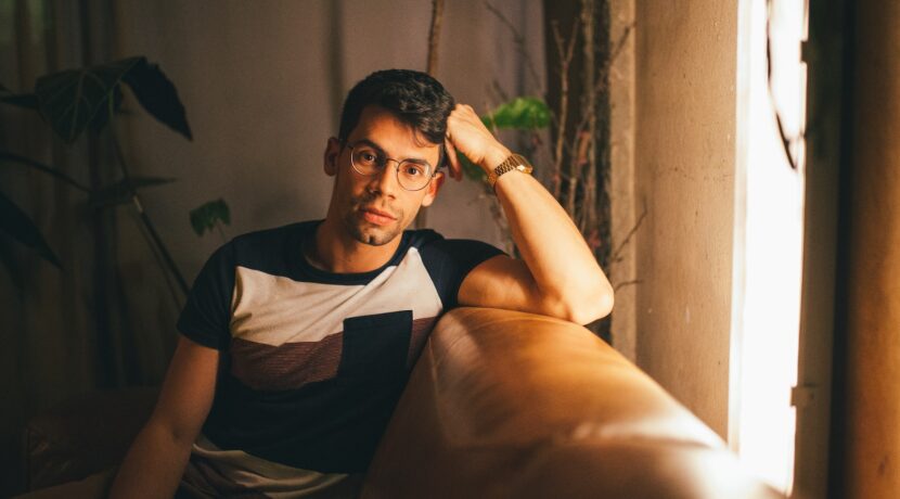 man in black and white crew neck t-shirt sitting on brown sofa