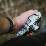 person holding silver point-and-shoot camera