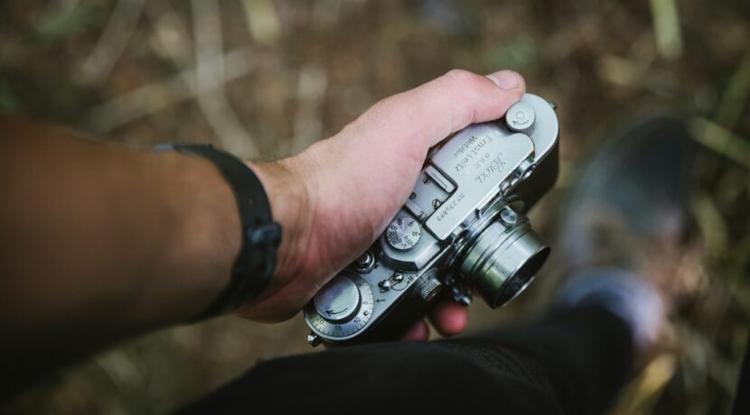 person holding silver point-and-shoot camera