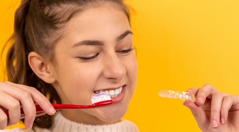 smiling girl in white sweater holding red and white toothbrush