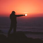 person standing on rock near body of water