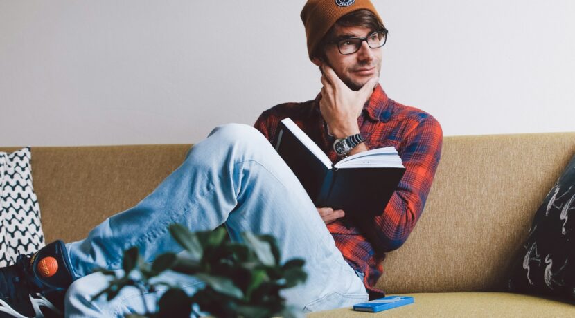 man sitting on sofa while holding book