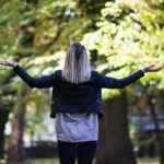 woman in black long-sleeved top in front of green leafed tree
