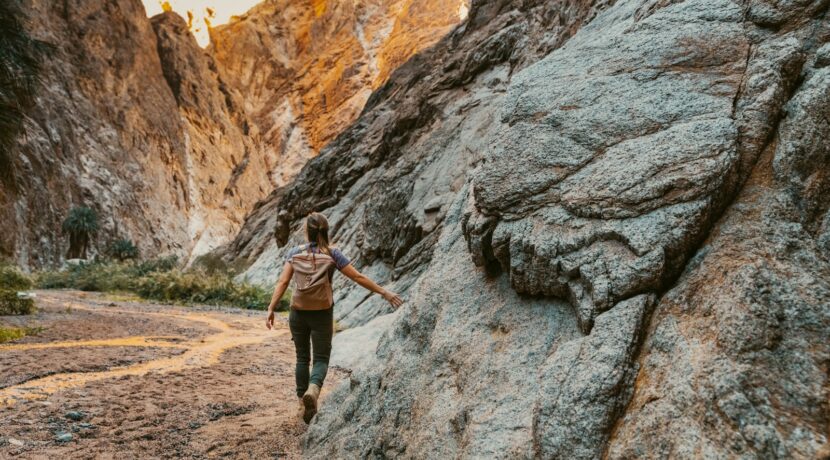 a woman climbing up a large rock in the mountains