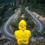 person in yellow coat standing on top of hill