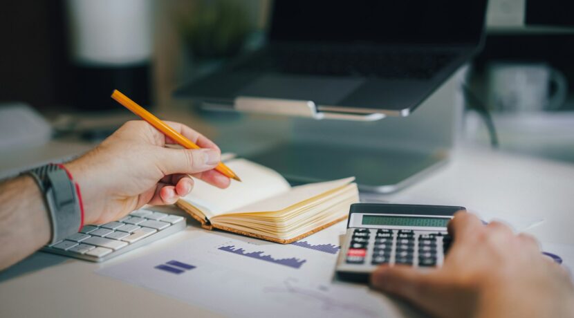 a person sitting at a desk with a calculator and a notebook