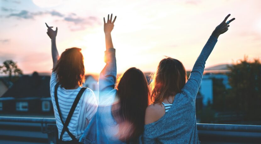 photo of three women lifting there hands
