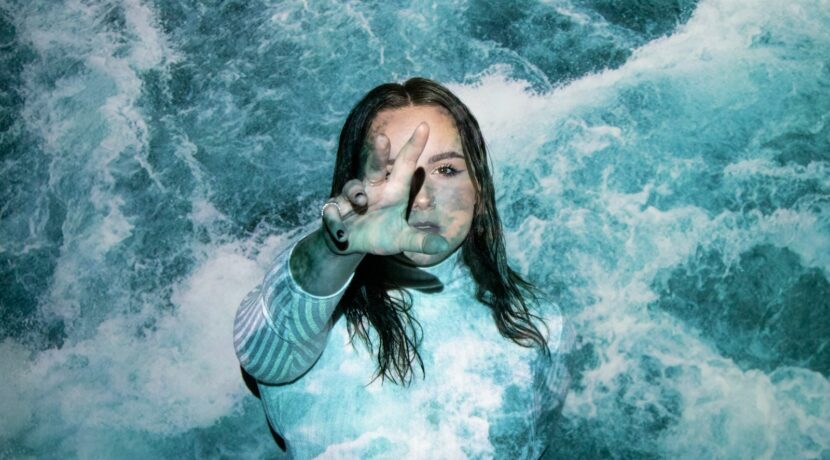 a woman is standing in the water with her hands in the air
