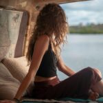 woman wearing black spaghetti strap top sitting viewing body of water